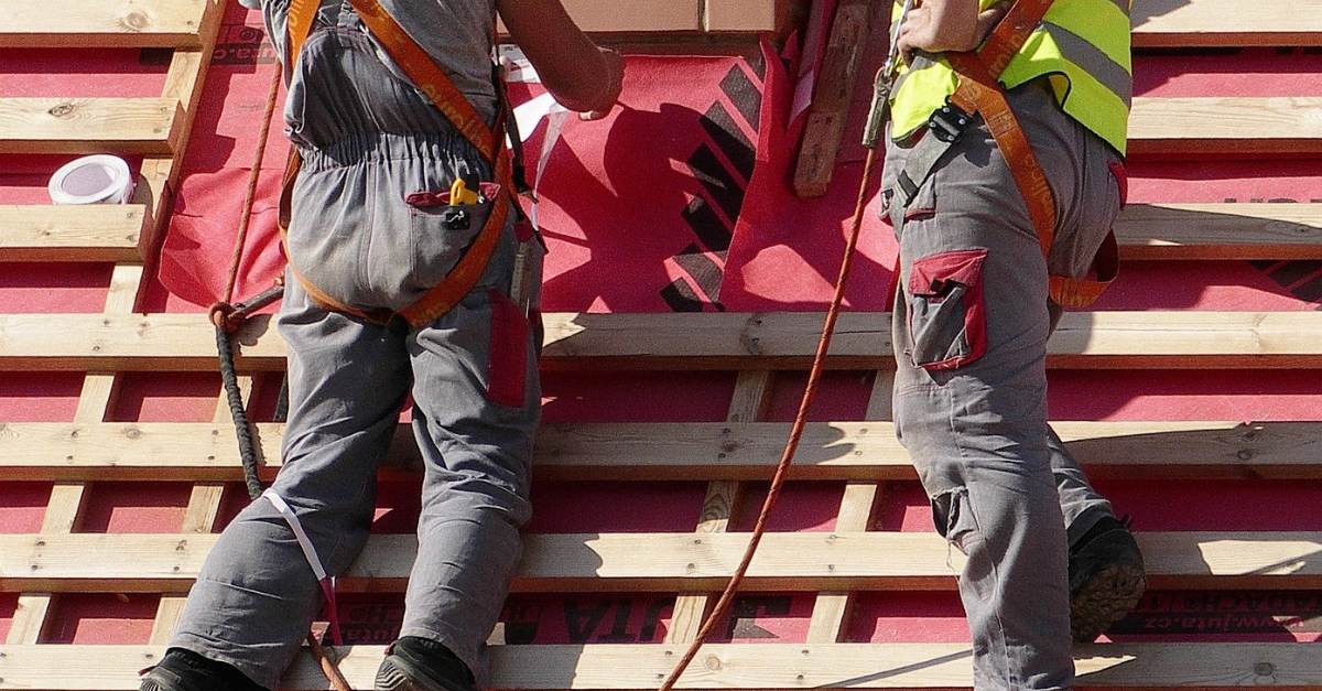 men working on roof with safety gear