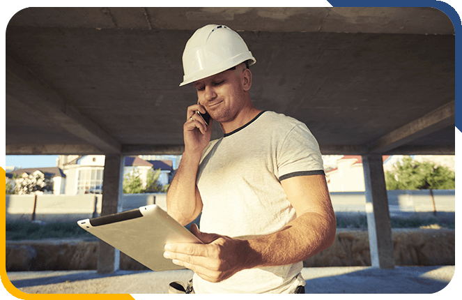 Construction worker having a phone call while on a tablet